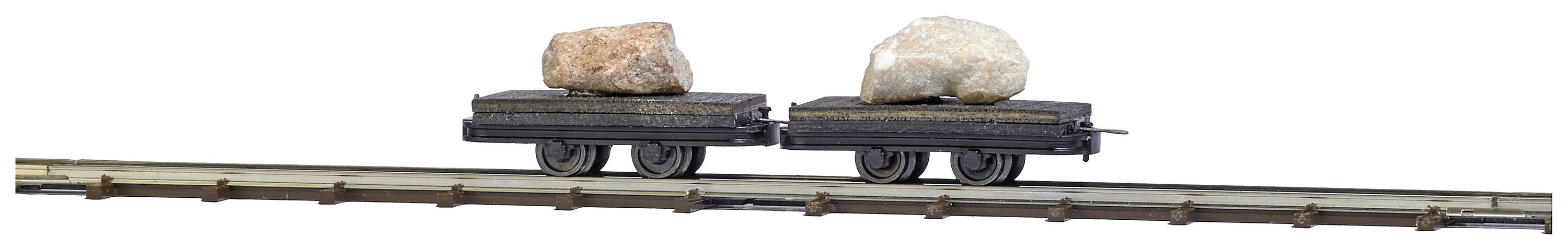Deux wagons de train miniature sur une voie, chacun chargé d'une grande pierre.
