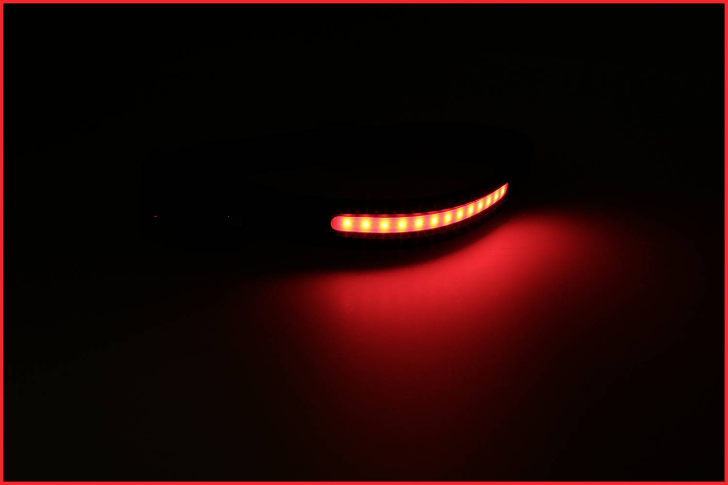 Une bande LED rouge vive dans un environnement sombre, formant une ligne courbe. Elle émet une lumière rouge intense.