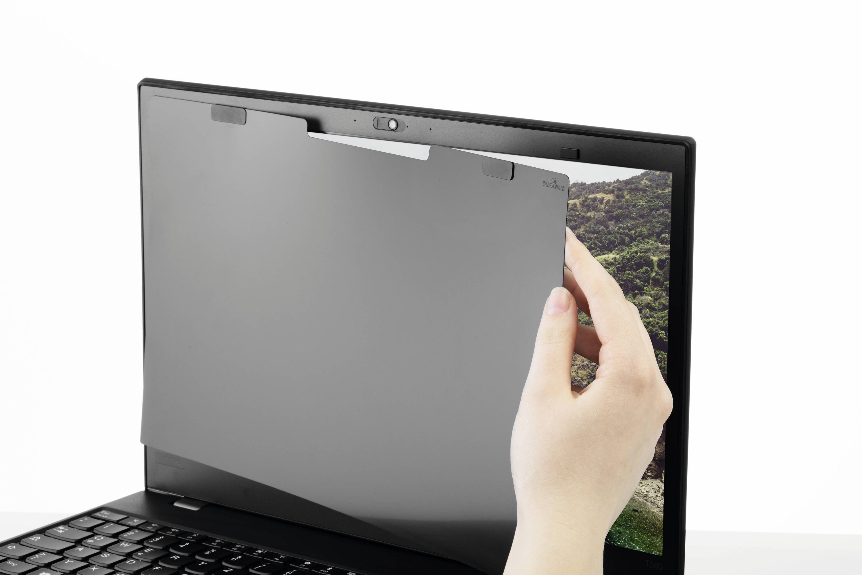 Un filtre de confidentialité est appliqué par une main sur l'écran d'un ordinateur portable. Le filtre réduit l'angle de vision de l'écran.