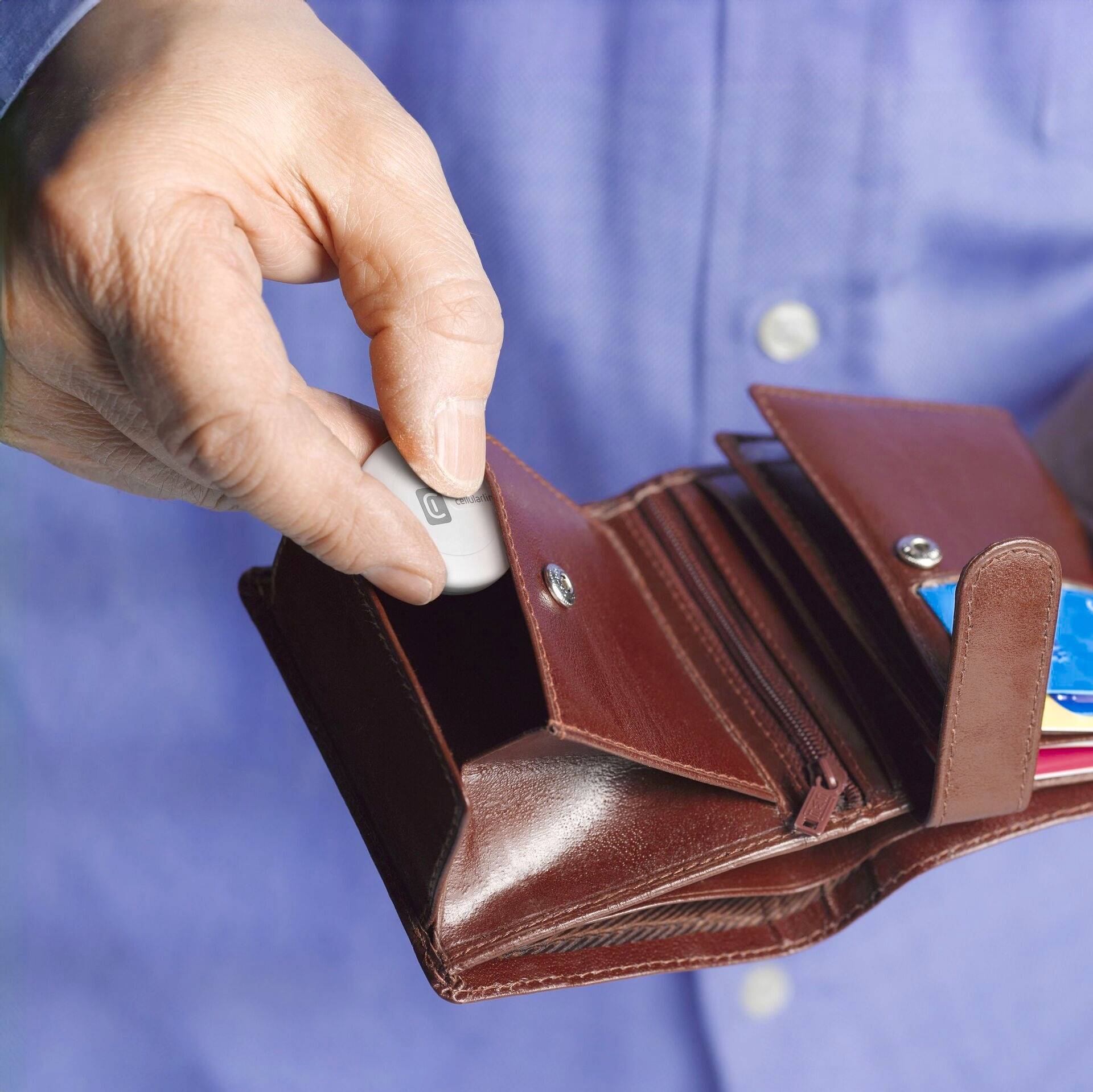 Une main tient un portefeuille brunâtre ouvert. Une clé USB en est retirée. Des cartes de crédit sont visibles à côté.