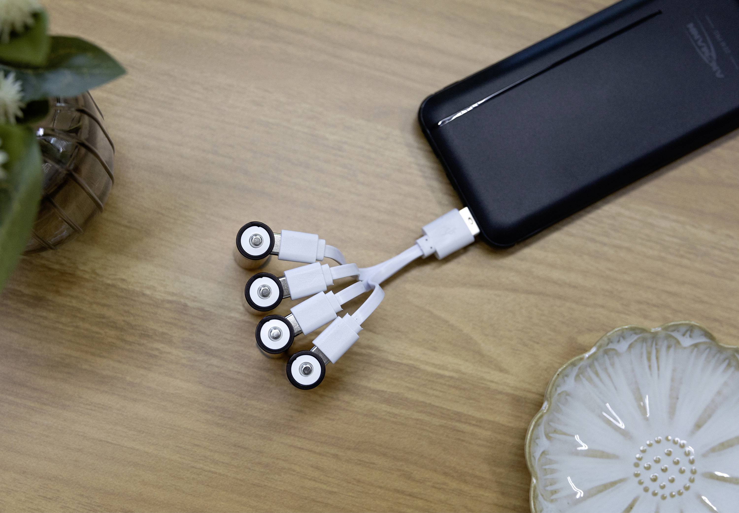 Un appareil doté d'un câble USB à cinq branches est placé sur une table en bois.