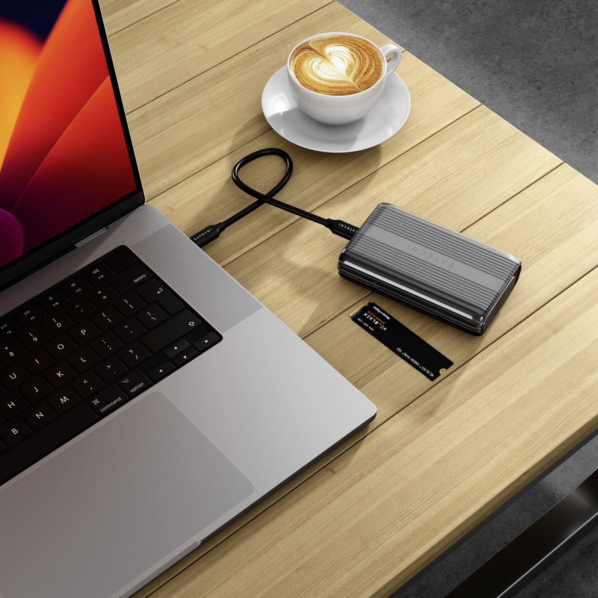 Ordinateur portable avec disque dur externe, carte de crédit et cappuccino sur une table en bois.