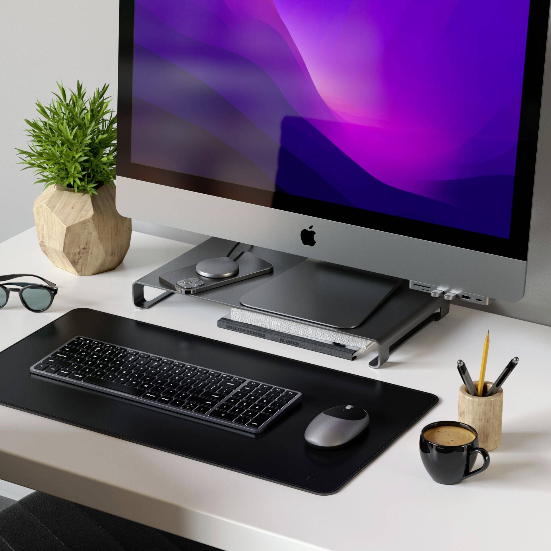 Un bureau d'ordinateur moderne avec un grand écran, un clavier et une souris. Sur le bureau se trouvent une tasse de café et une plante.