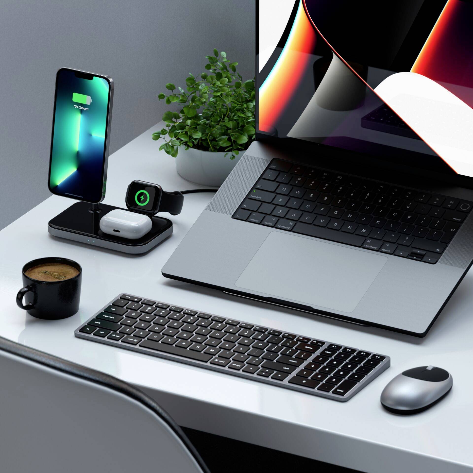 Sur un bureau se trouvent un ordinateur portable, une station de charge sans fil avec un smartphone, une tasse de café, un clavier, une souris et une plante.