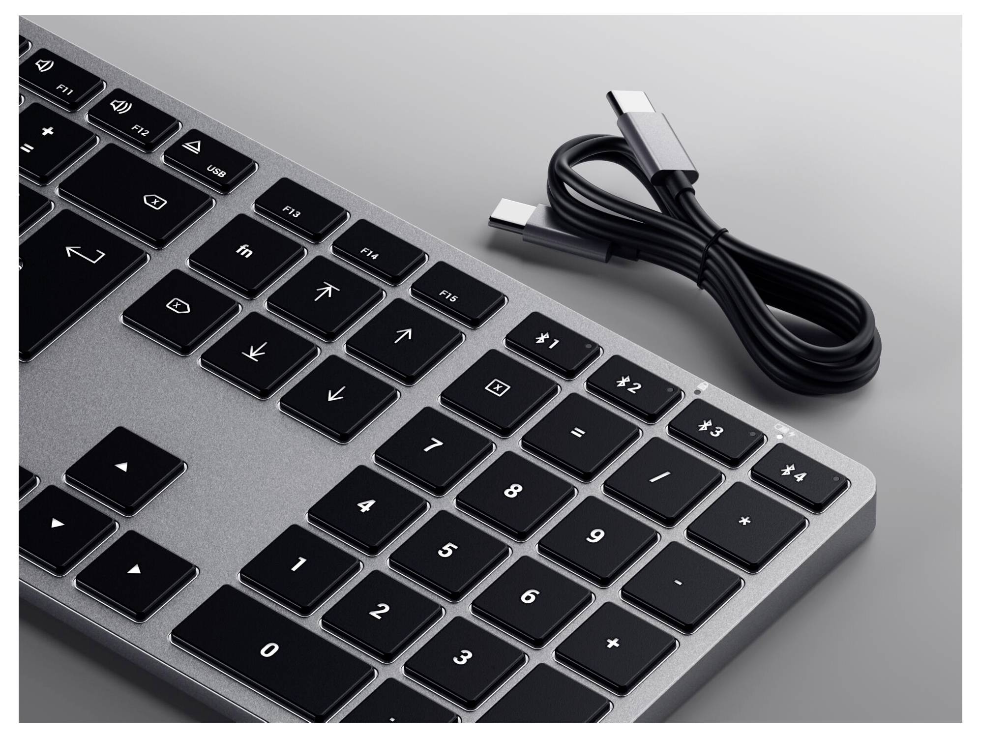 Clavier avec touches noir et gris et un câble USB détaché.