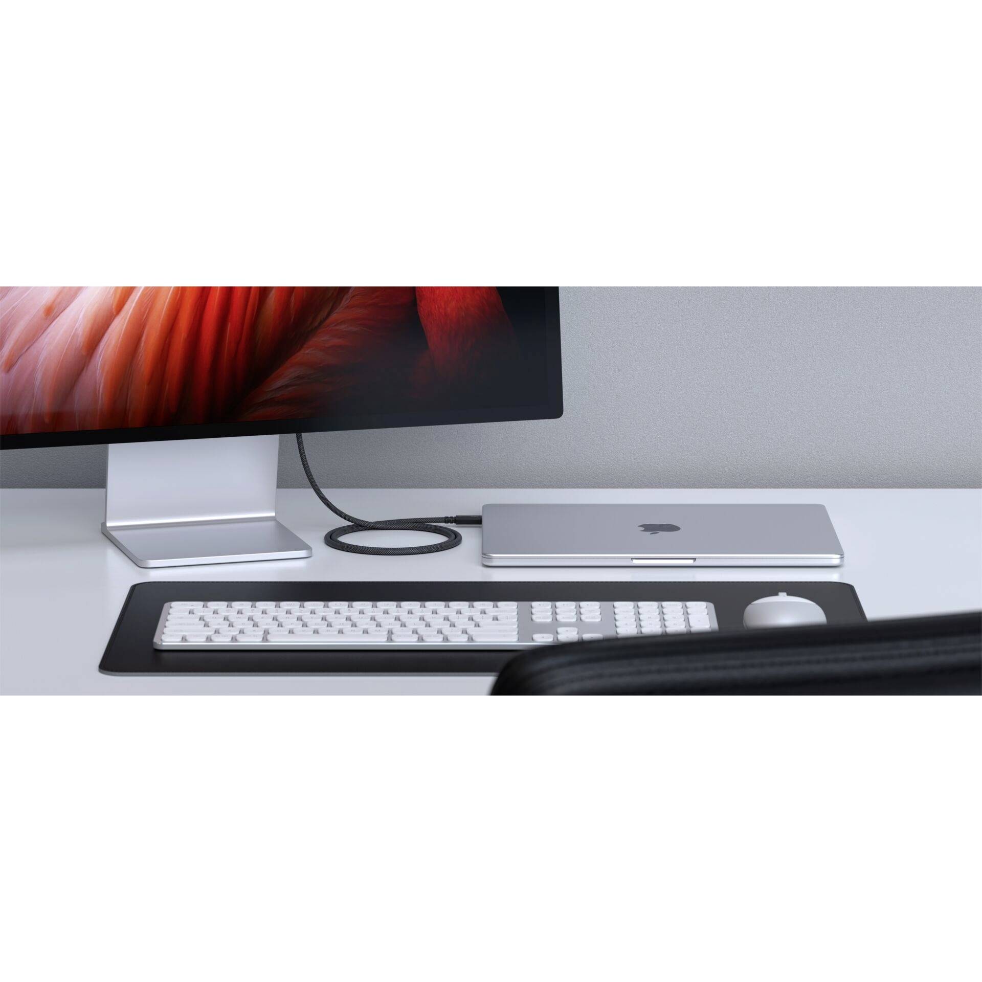 Bureau avec un moniteur, un ordinateur portable fermé, un clavier et une souris. L'écran affiche un design abstrait rouge.