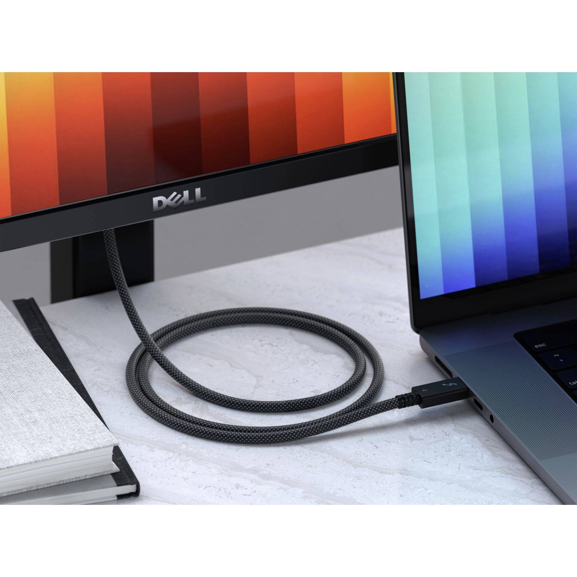 Un bureau avec un ordinateur portable et un écran connectés par un câble. L'écran affiche des bandes verticales colorées.