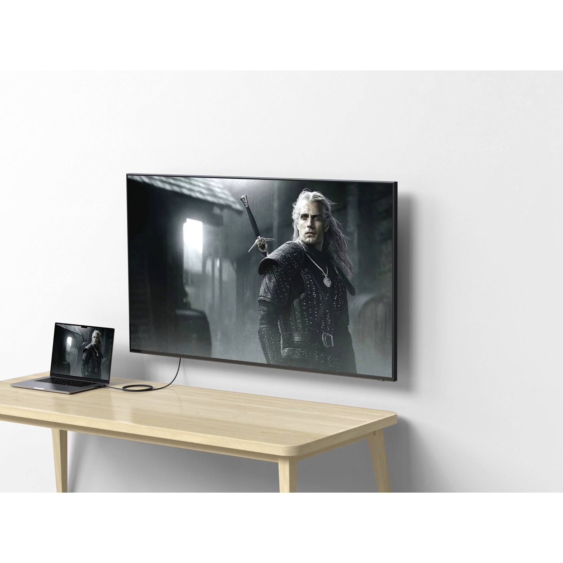 Un ordinateur portable est connecté à un téléviseur qui affiche une scène de film montrant un guerrier médiéval vêtu de noir.