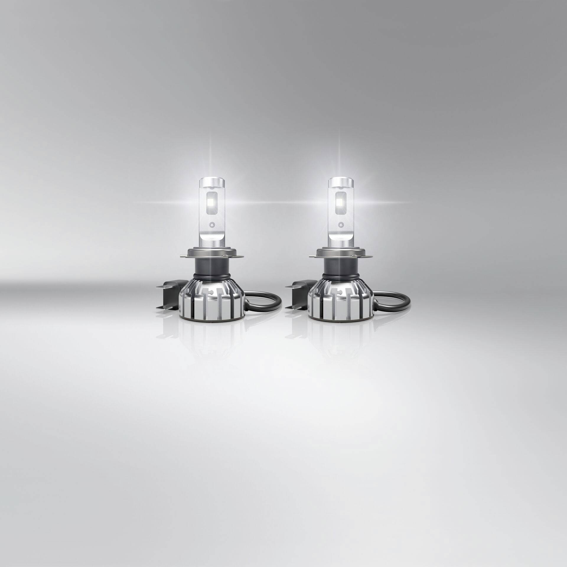 Deux phares de voiture à LED s'illuminent sur une surface réfléchissante, diffusant une lumière blanche et vive.