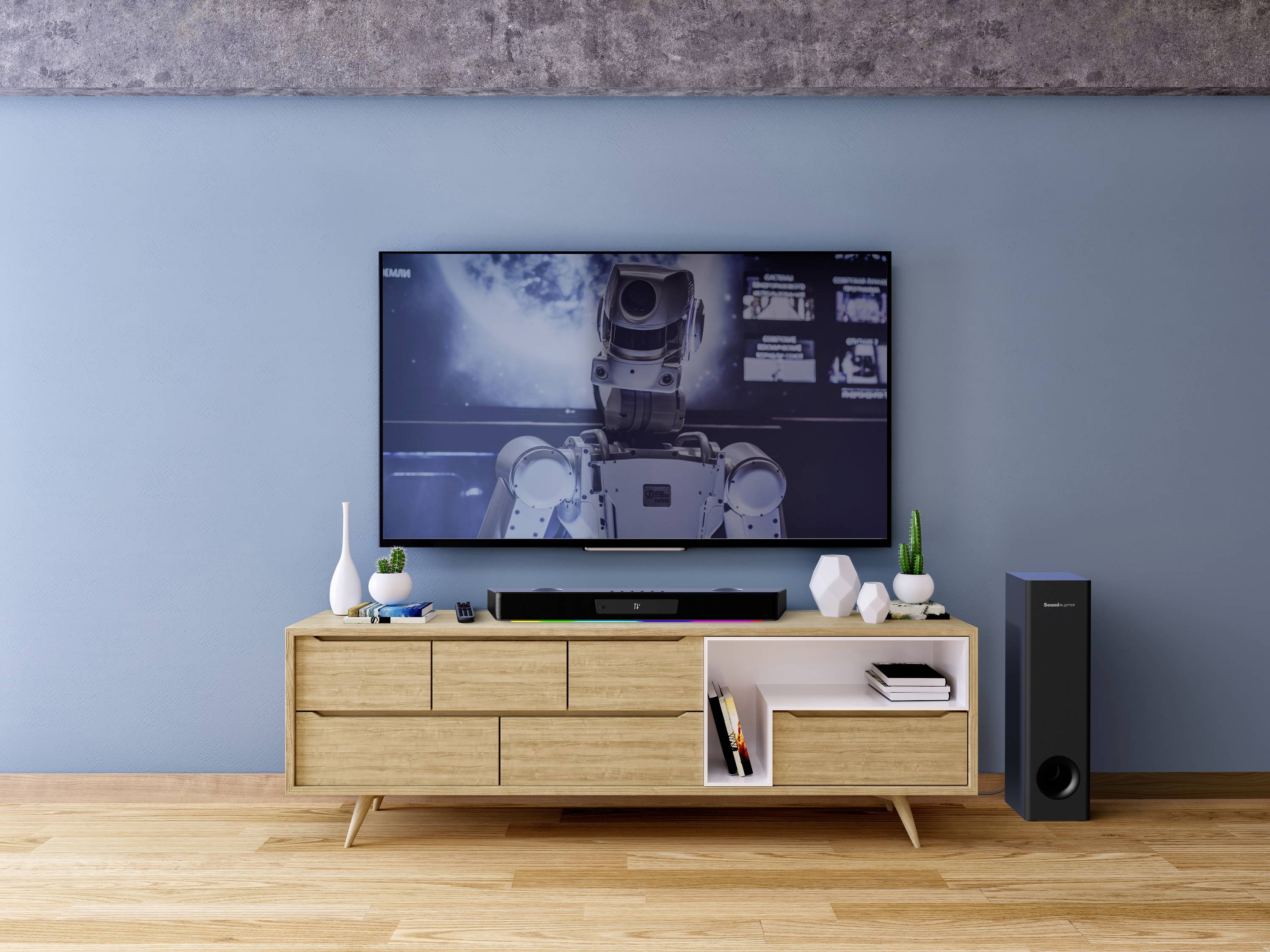 Un téléviseur moderne sur un meuble en bois affiche une image d'un robot dans l'espace. À côté, des enceintes et de petits objets décoratifs.