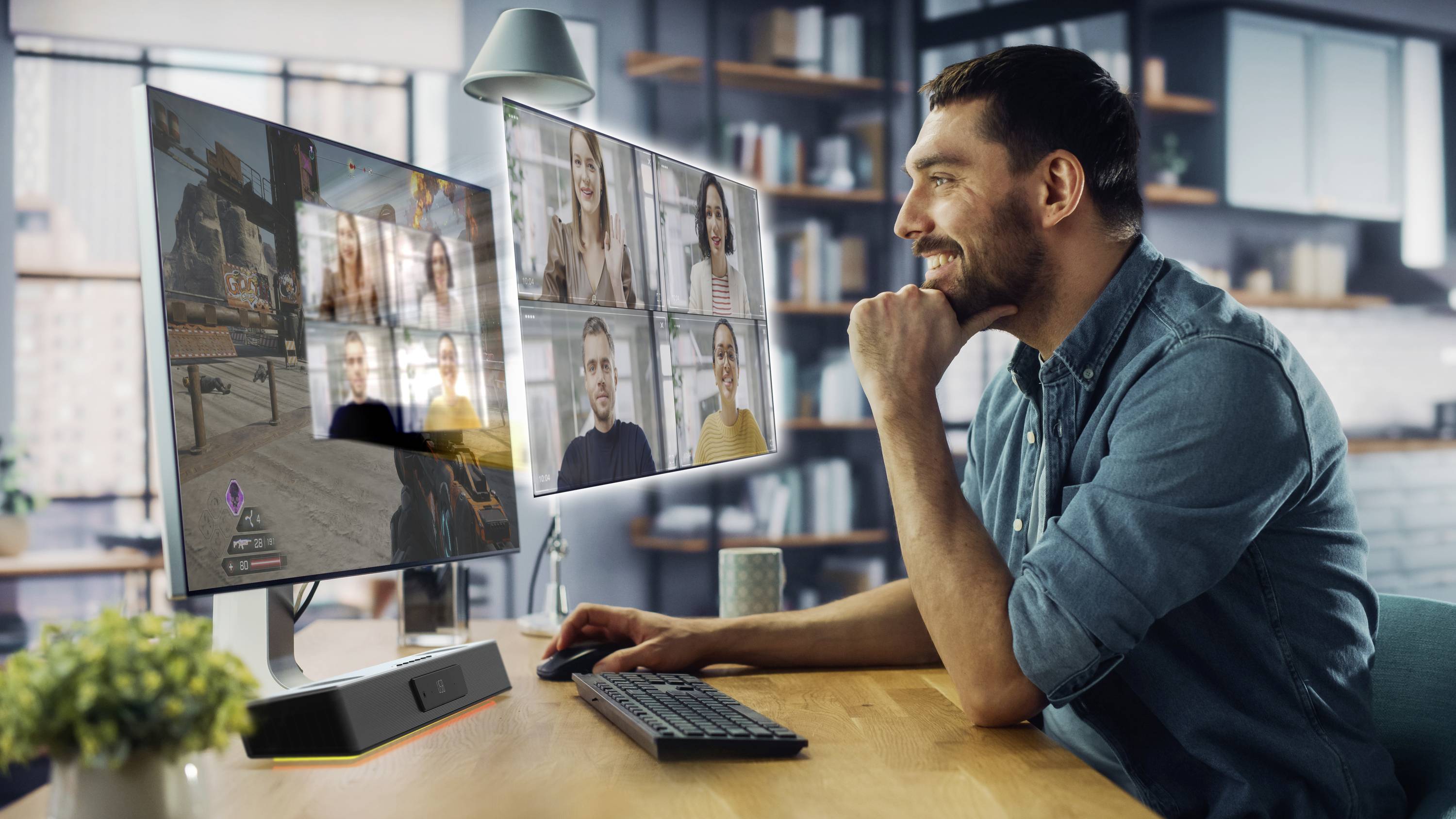Un homme est assis à un bureau avec deux écrans. Sur un écran, un jeu vidéo est visible, sur l'autre un appel de visioconférence.