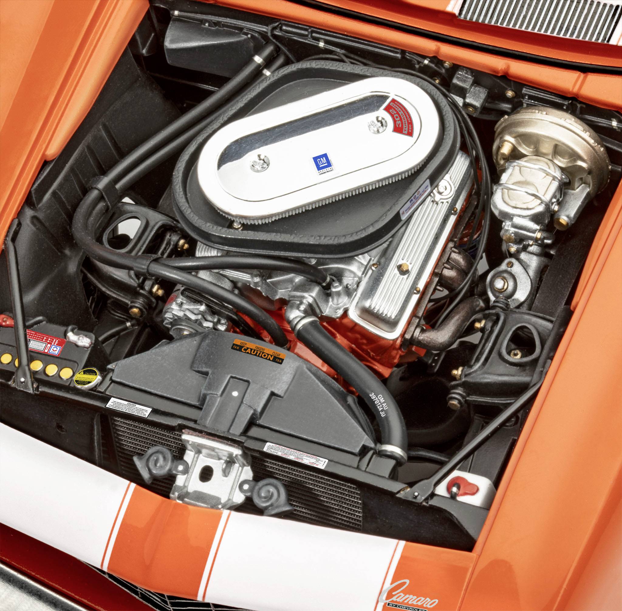 Un compartiment moteur ouvert d'une voiture de sport orange, révélant un moteur aux détails minutieux avec des composants argentés et noirs.