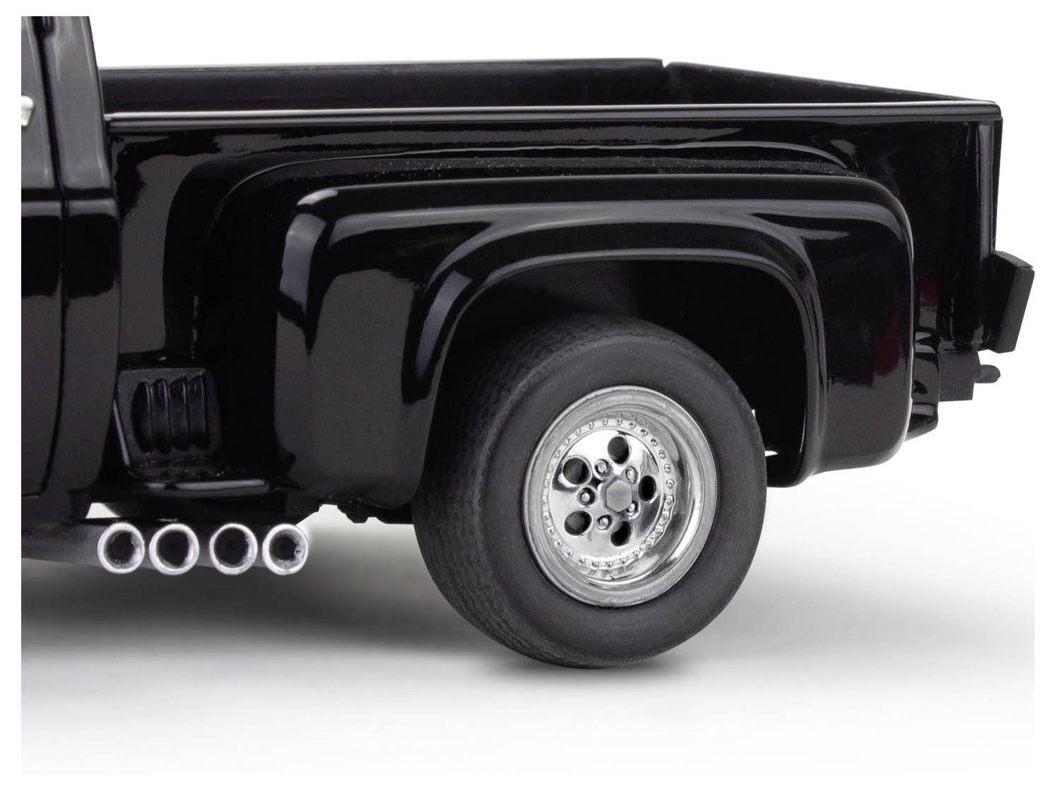 Vue partielle d'un pick-up noir, avec un focus sur la roue arrière et le pot d'échappement à plusieurs sorties.