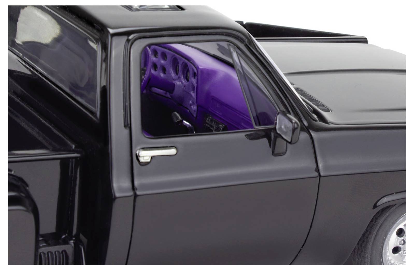 Voiture miniature noire avec intérieur violet, vue à travers la fenêtre latérale, montrant le tableau de bord et le volant.