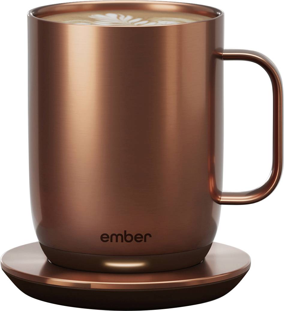 Tasse en cuivre avec un dessous de verre portant l'inscription 'ember', contenant une boisson décorée de latte art.