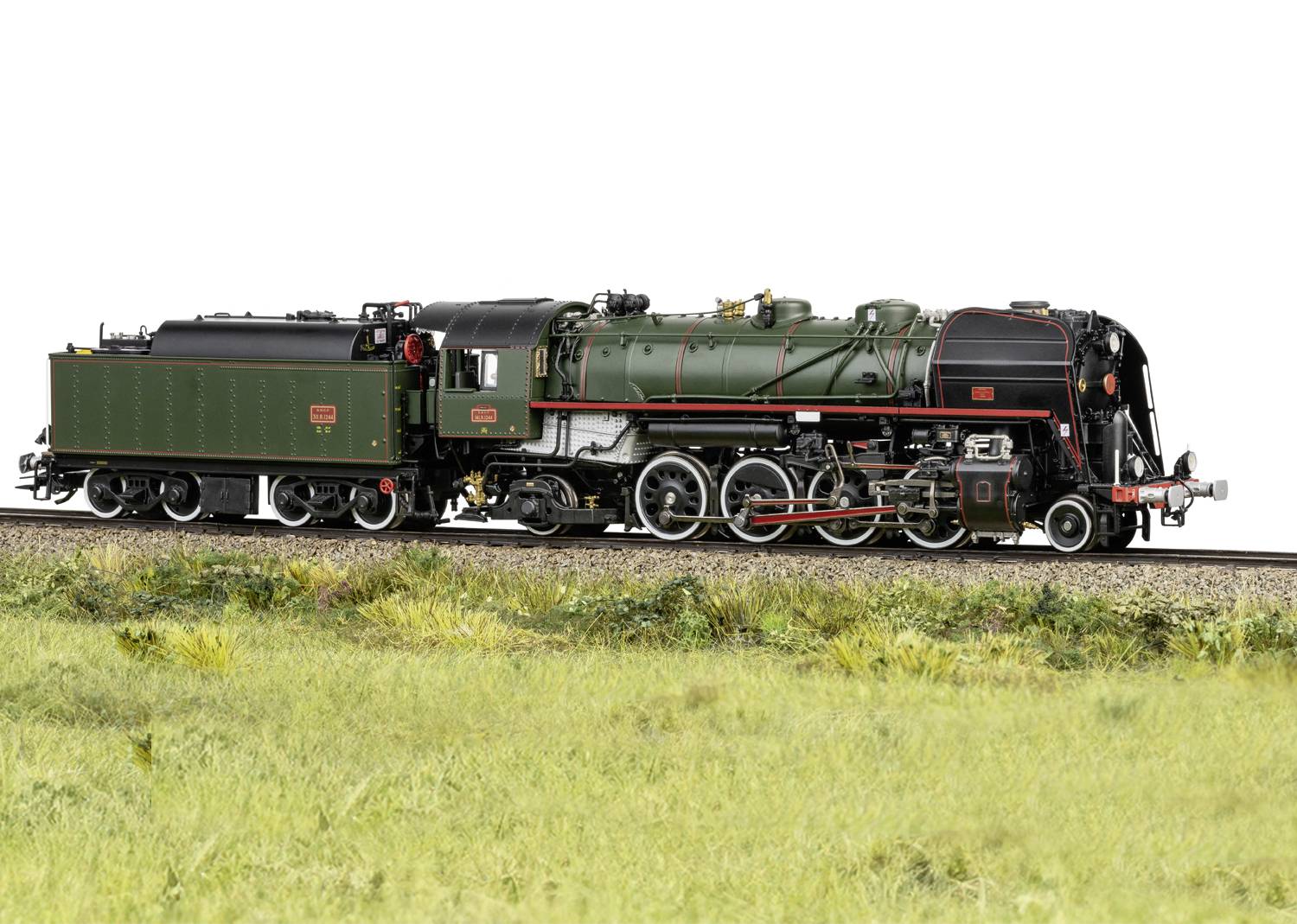 Locomotive à vapeur verte historique sur des rails de chemin de fer avec un pré au premier plan. La locomotive présente des détails noirs et des marquages rouges.
