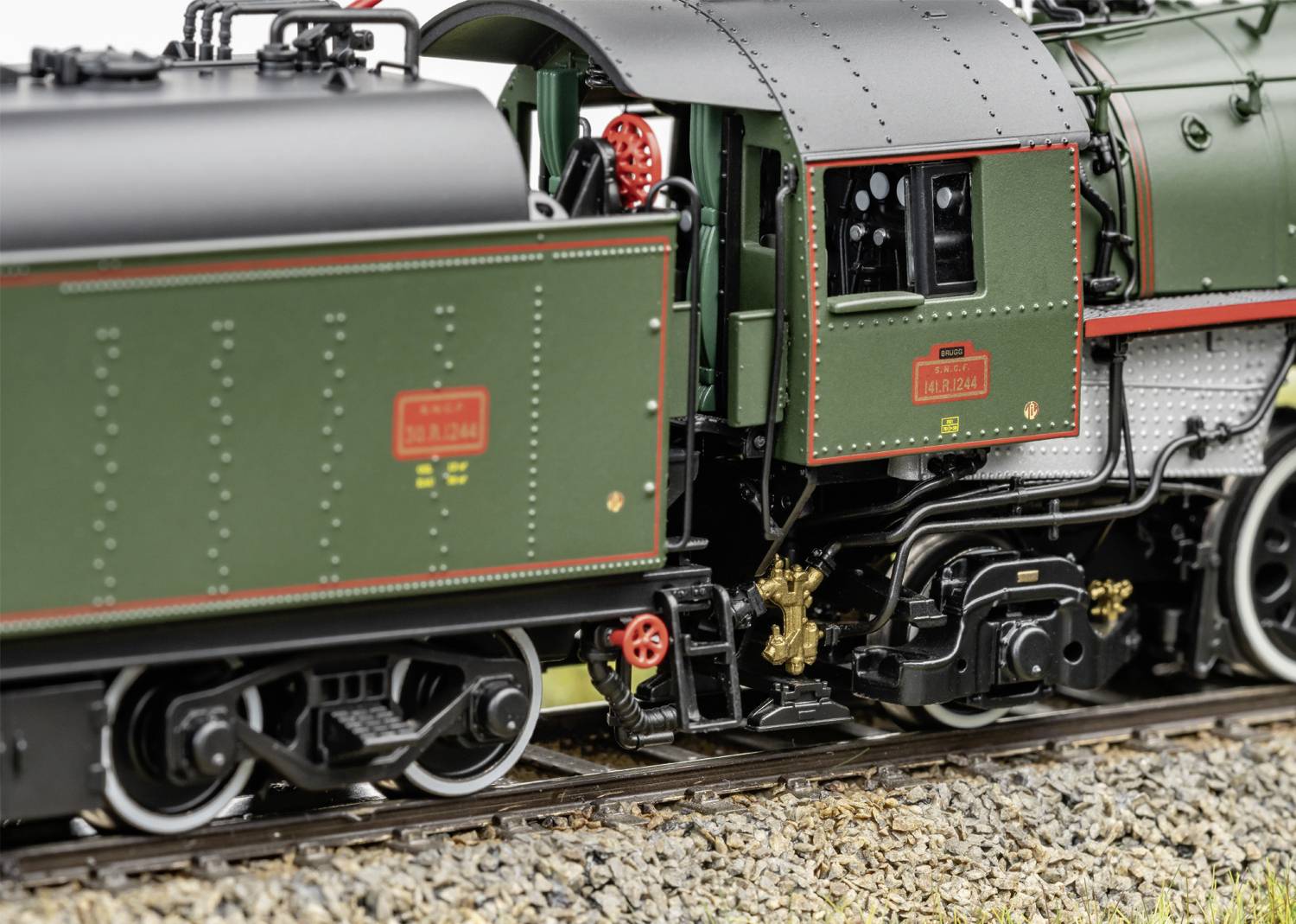 Un train miniature sur un rail montre des éléments détaillés comme des roues et des plaques signalétiques dans un gros plan.