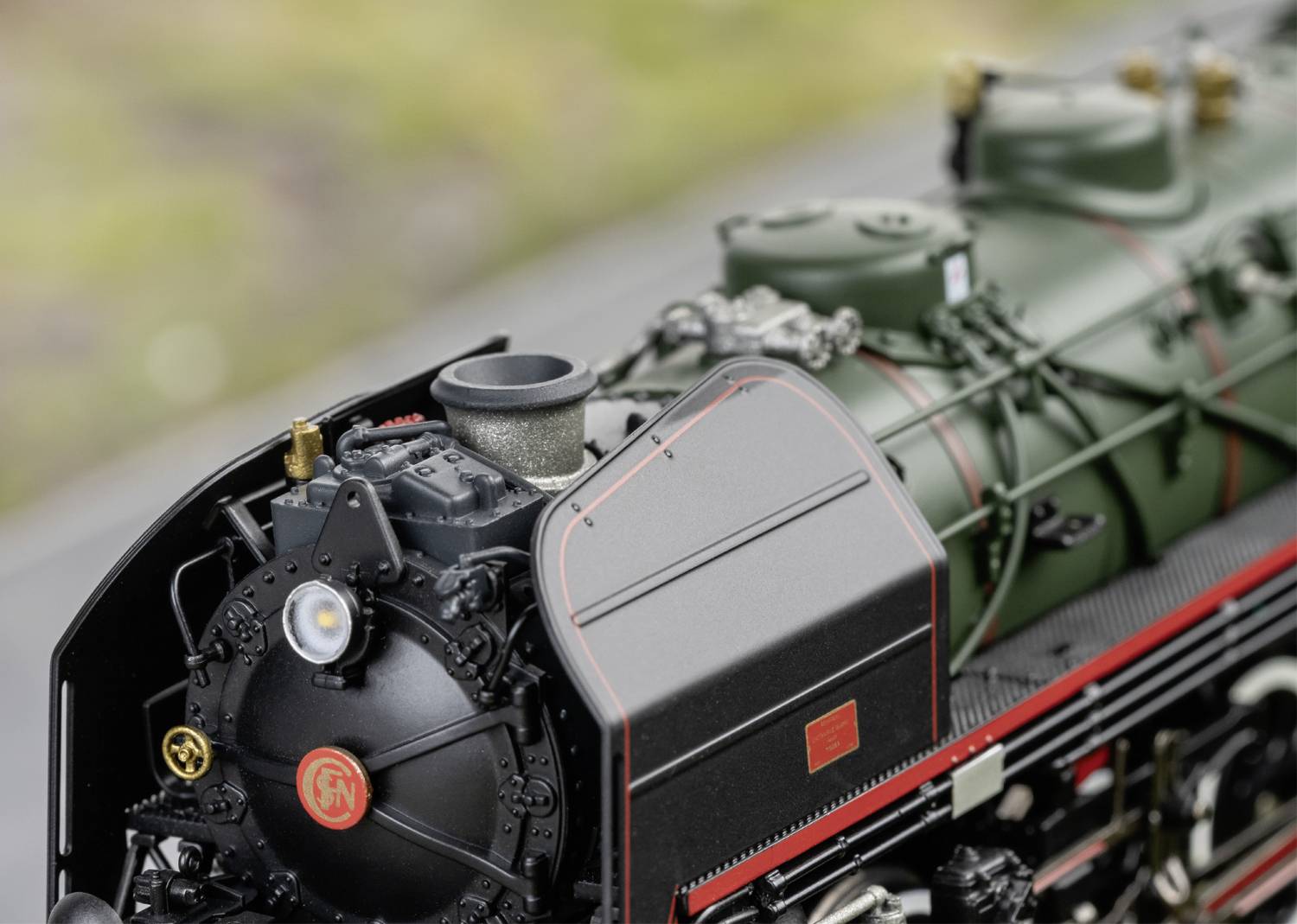 Gros plan sur une locomotive à vapeur classique avec une peinture noire et rouge, révélant les détails de sa mécanique et de son design.