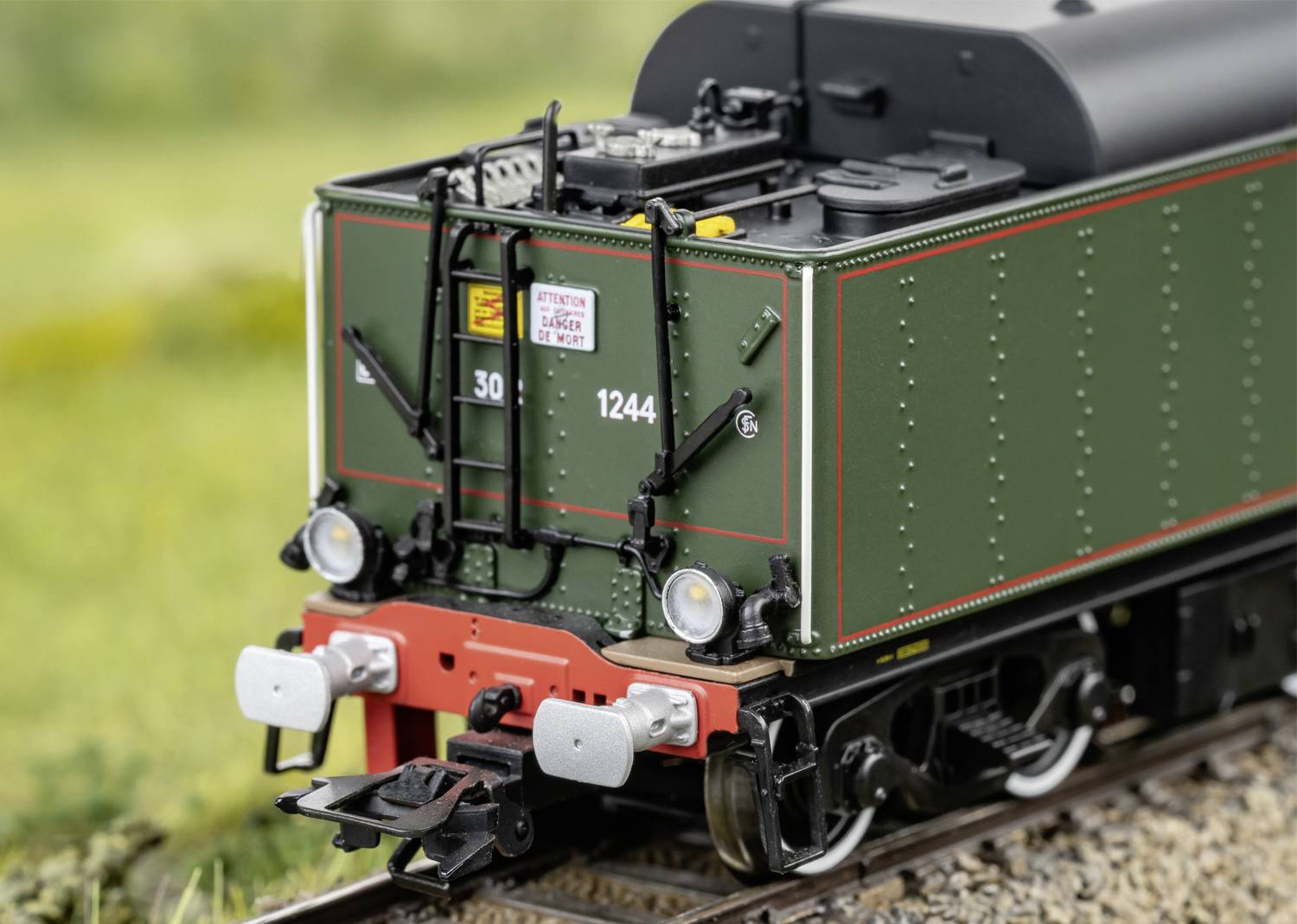 Un train miniature peint en vert, portant le numéro '1244', est posé sur des rails dans un paysage rural. Conçu avec des détails riches et réalistes.