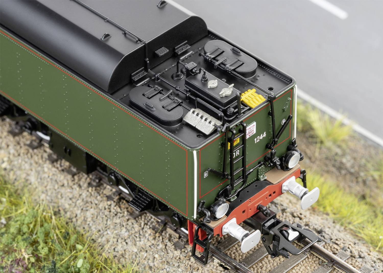 Locomotive à vapeur de train miniature avec peinture verte et réservoir d'eau détaillé sur une section de voie ferrée.
