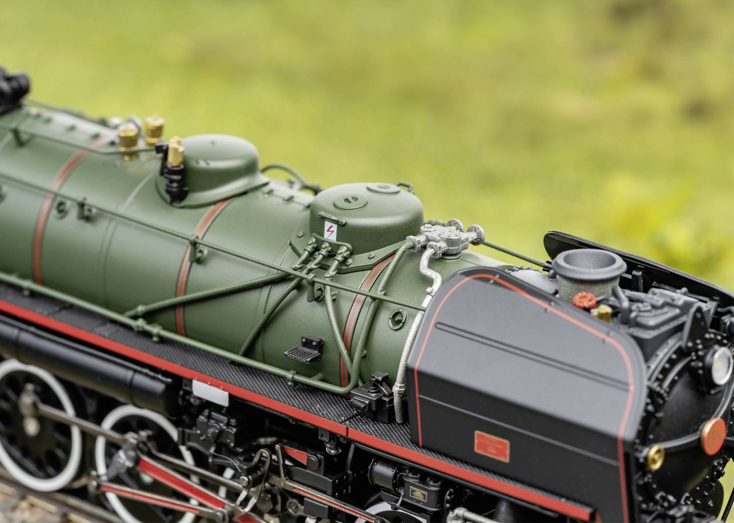 Modèle d'une locomotive à vapeur historique avec une chaudière verte, une cabine de conduite noire, des détails rouges et des soupapes argentées au premier plan.