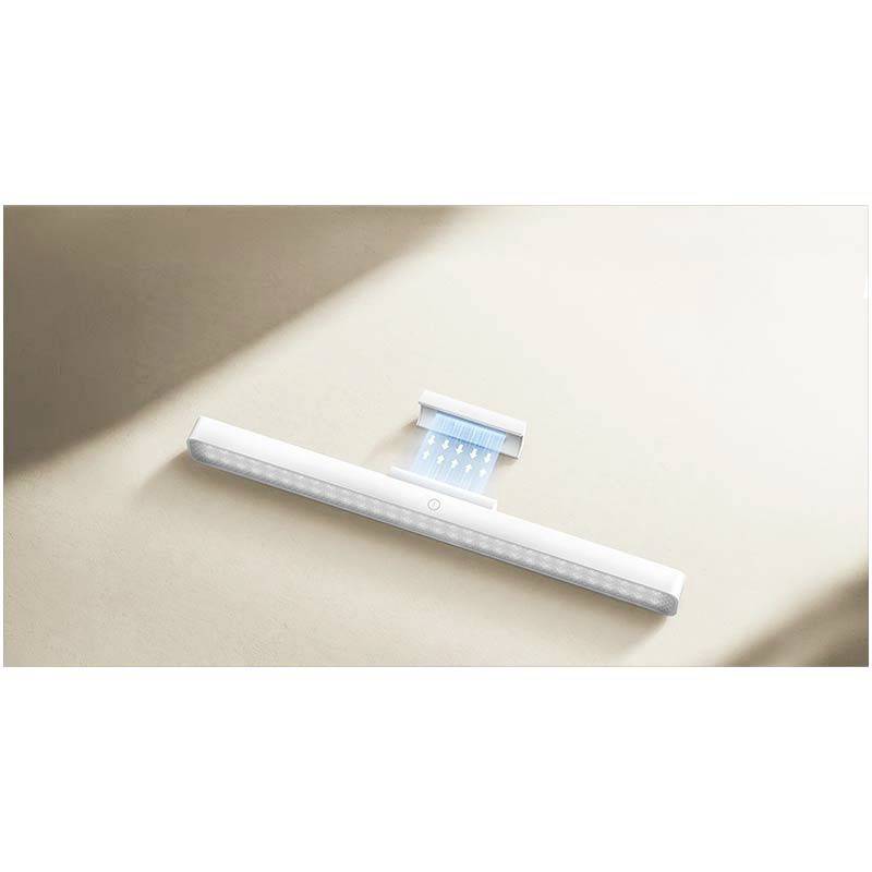 Un luminaire LED plat et blanc, à l'esthétique minimaliste, reposant sur une surface rectangulaire beige.
