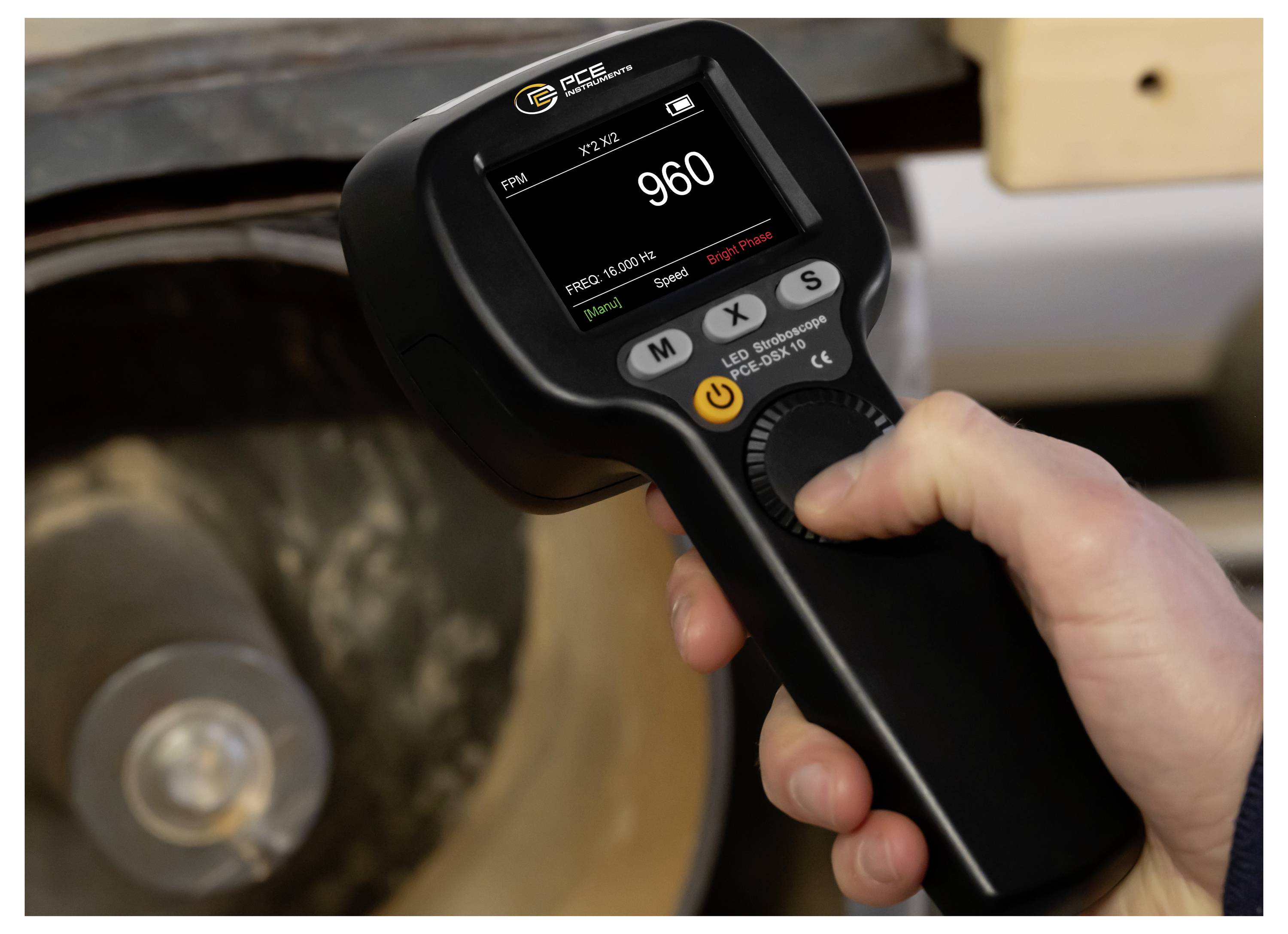 Tachymètre numérique portatif mesurant la vitesse d'une roue, affichant 960 RPM sur son écran.