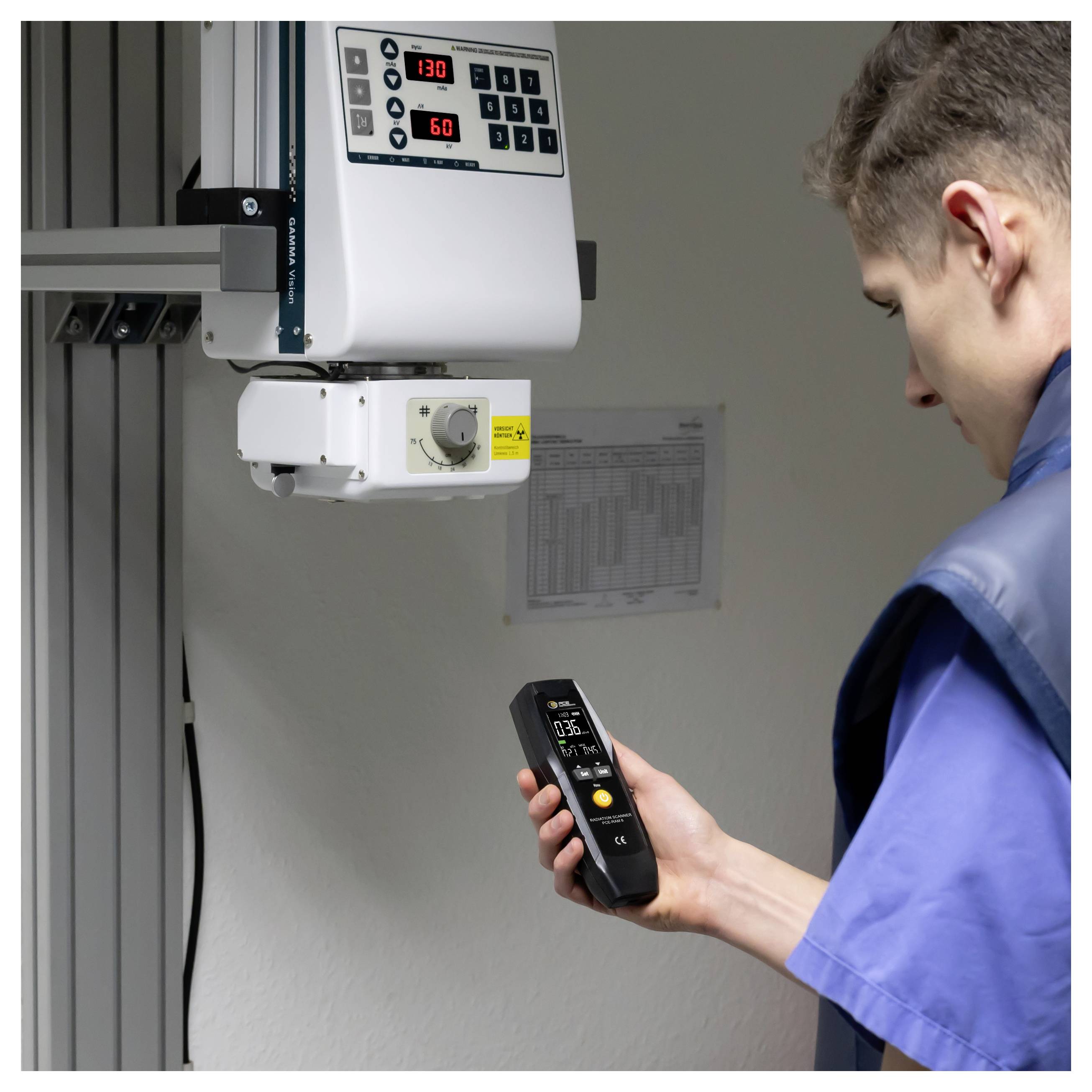 Technicien utilisant un appareil de mesure portatif pour inspecter un dispositif industriel fixé au mur avec écran numérique et commandes.
