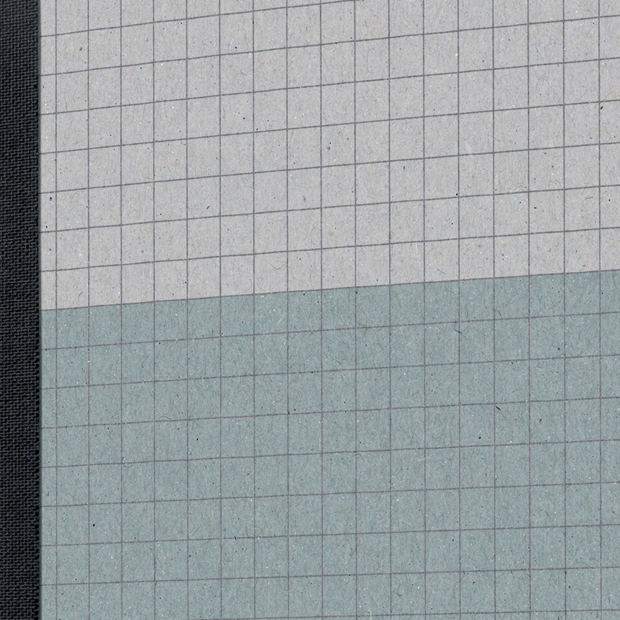 Un carnet à carreaux avec une grille grise et bleue, adapté au dessin ou à la prise de notes. Une couverture noire sur la gauche.