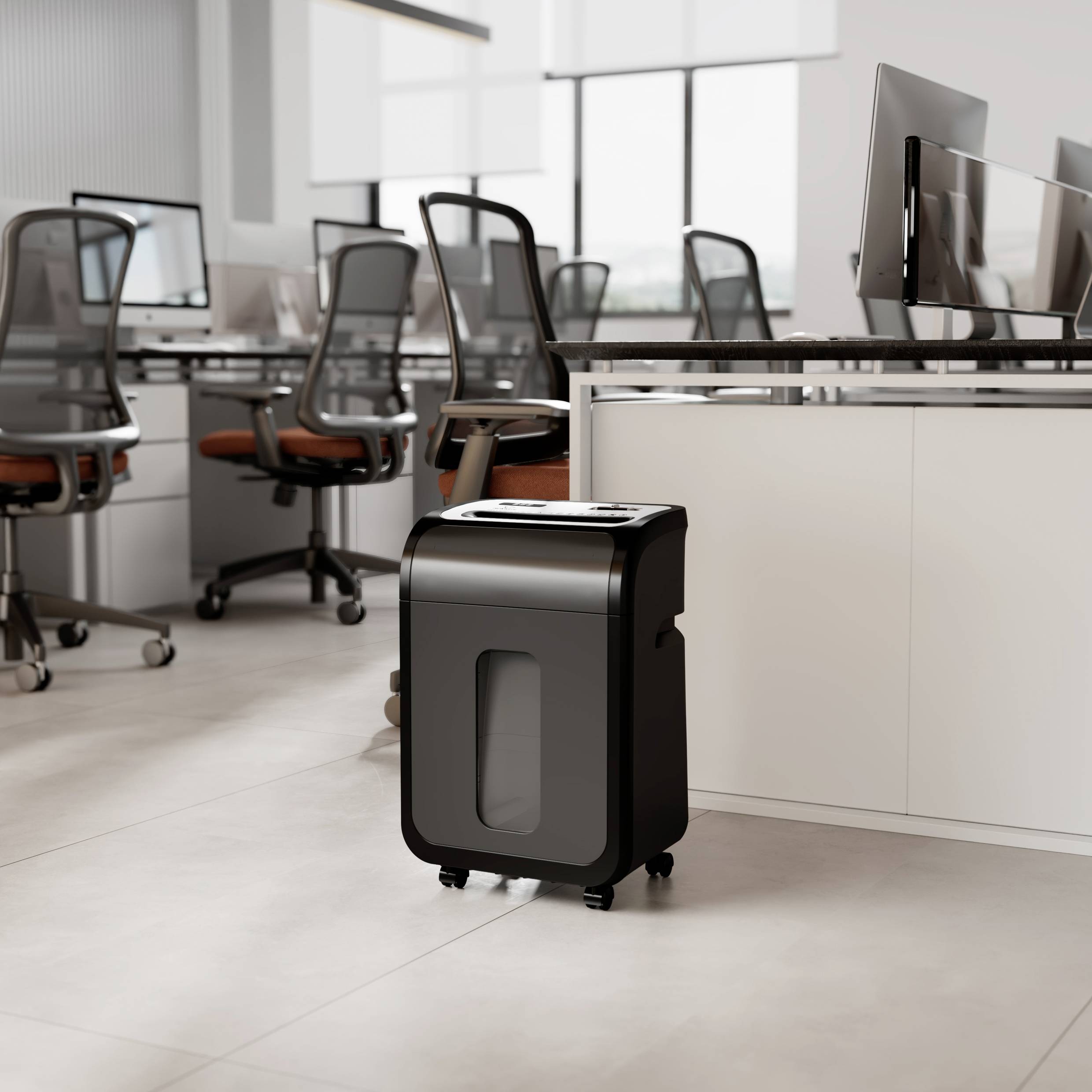 Un destructeur de documents se trouve dans un bureau moderne avec plusieurs chaises de bureau et des ordinateurs sur des bureaux blancs.