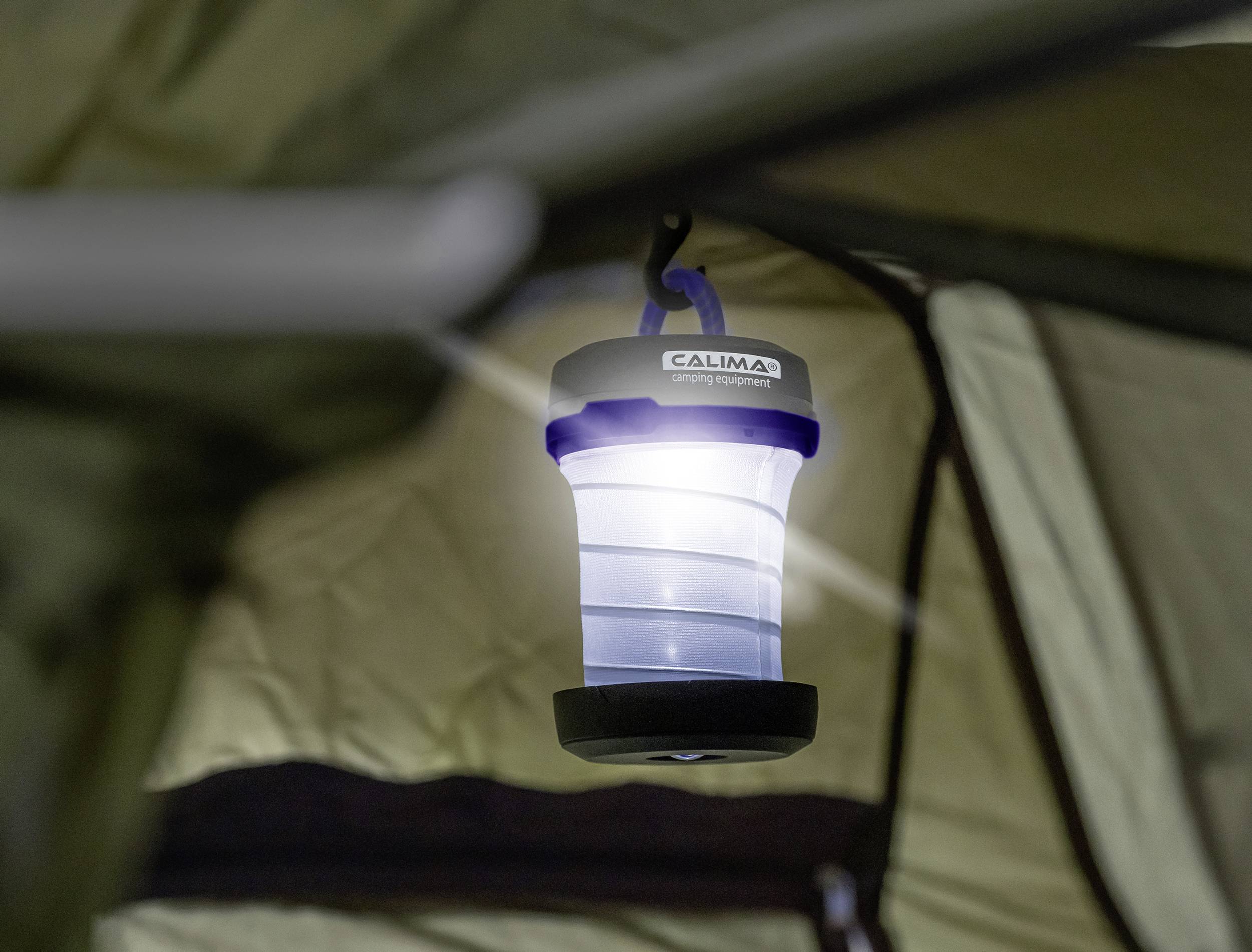 Une lanterne de camping est suspendue dans une tente et brille, illuminant l'intérieur. Idéale pour les aventures nocturnes sous la tente.