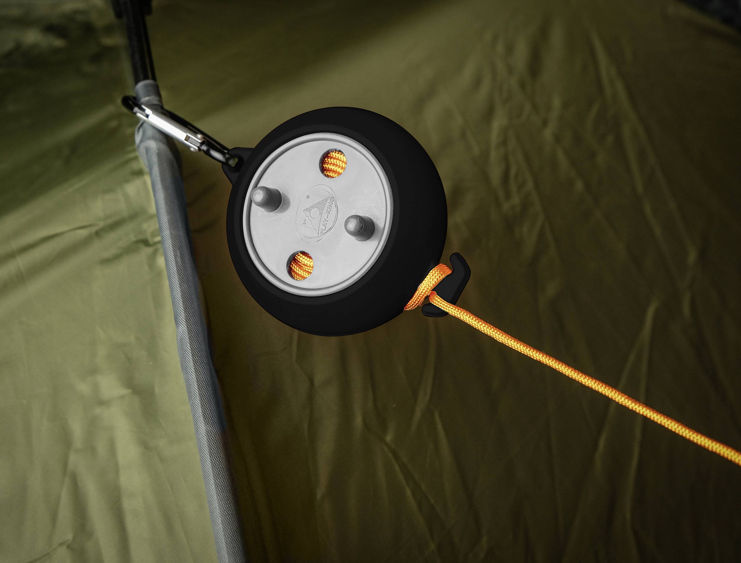 Une tente avec une corde orange attachée par un tendeur circulaire pour ajuster la tension du cordage.