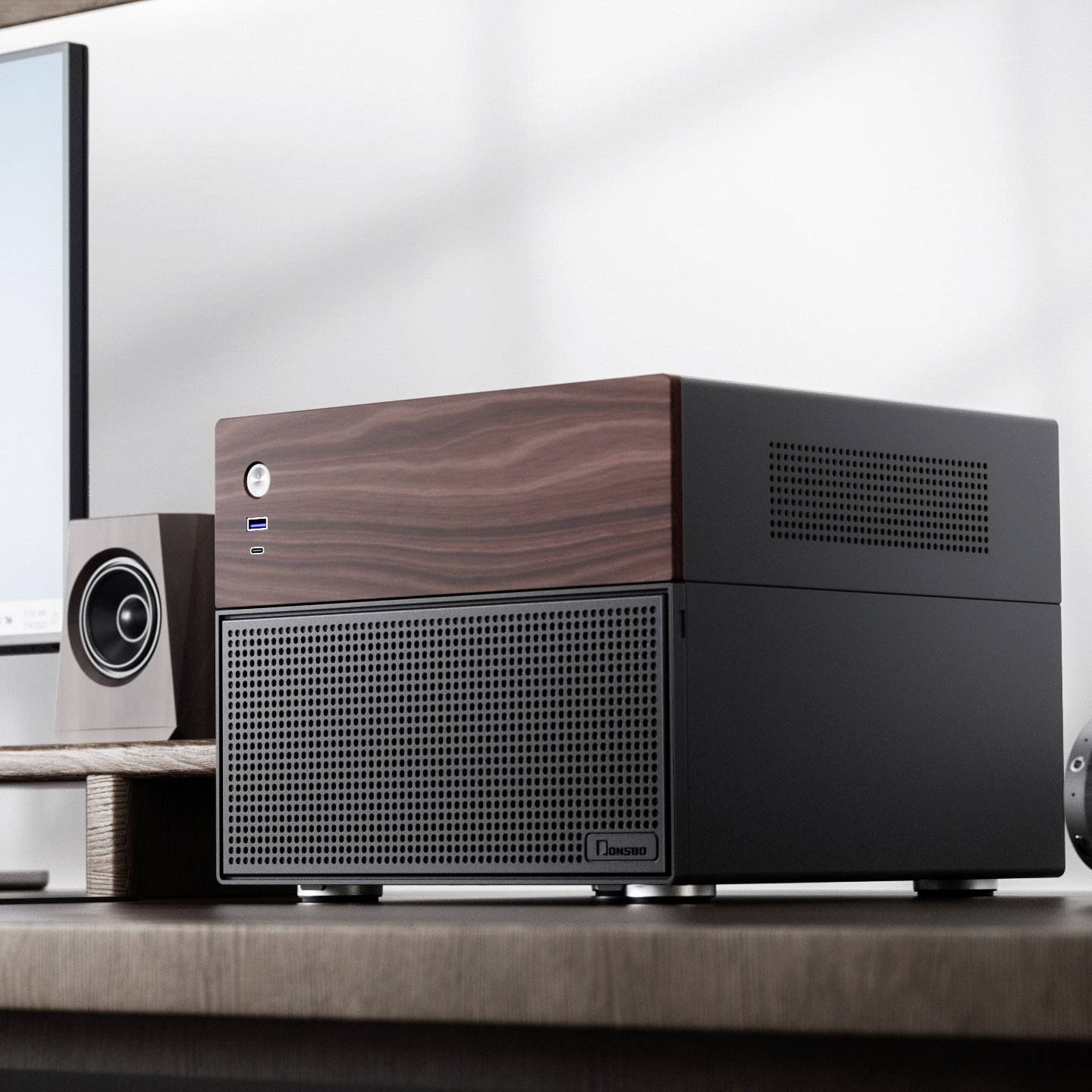 Tour d'ordinateur noir avec surface en bois sur un bureau, à côté d'un écran et de haut-parleurs. Design moderne et minimaliste.