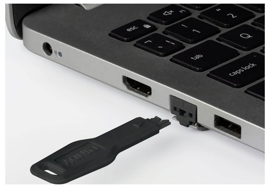 Clé USB insérée dans le port latéral d'un ordinateur portable près du clavier.