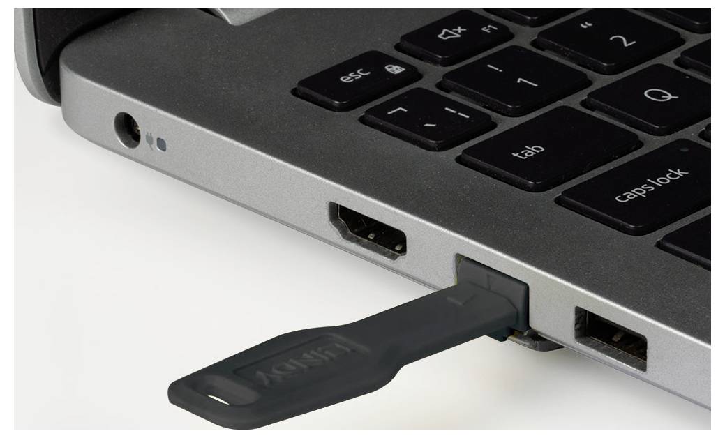 USB flash drive plugged into a laptop's USB port on the side of the keyboard.