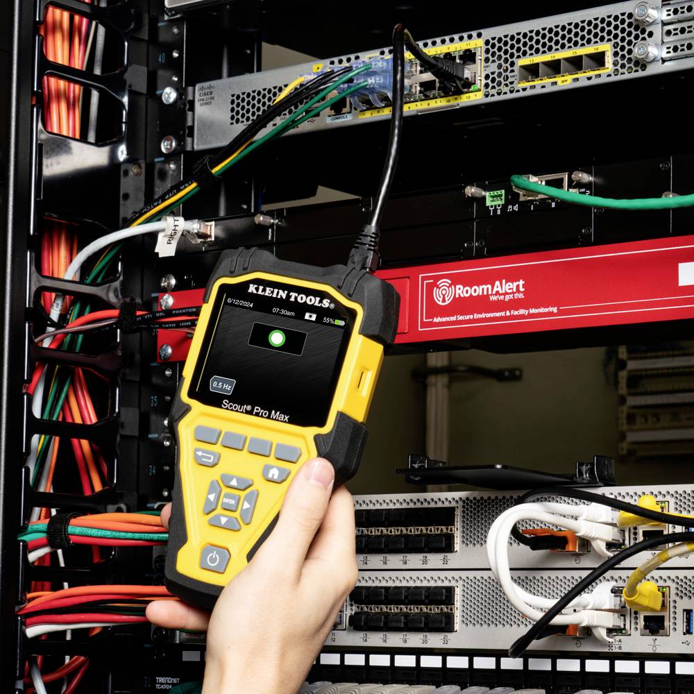 Une personne utilise un appareil de diagnostic jaune sur un rack de serveurs pour vérifier les connexions réseau. Des câbles sont visibles en arrière-plan.
