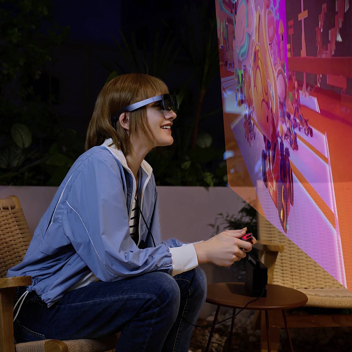 Une personne portant un casque de réalité virtuelle est assise et observe avec enthousiasme une projection virtuelle aux graphiques colorés.