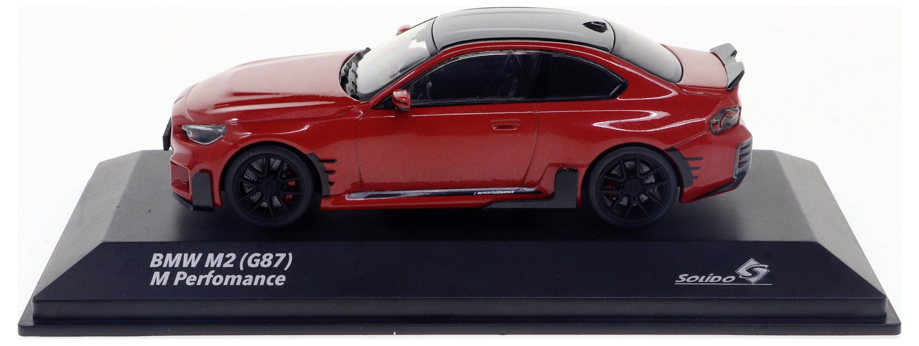 Voiture miniature rouge d'un BMW M2 (G87) M Performance sur un socle noir. Vue latérale avec jantes noires et détails.