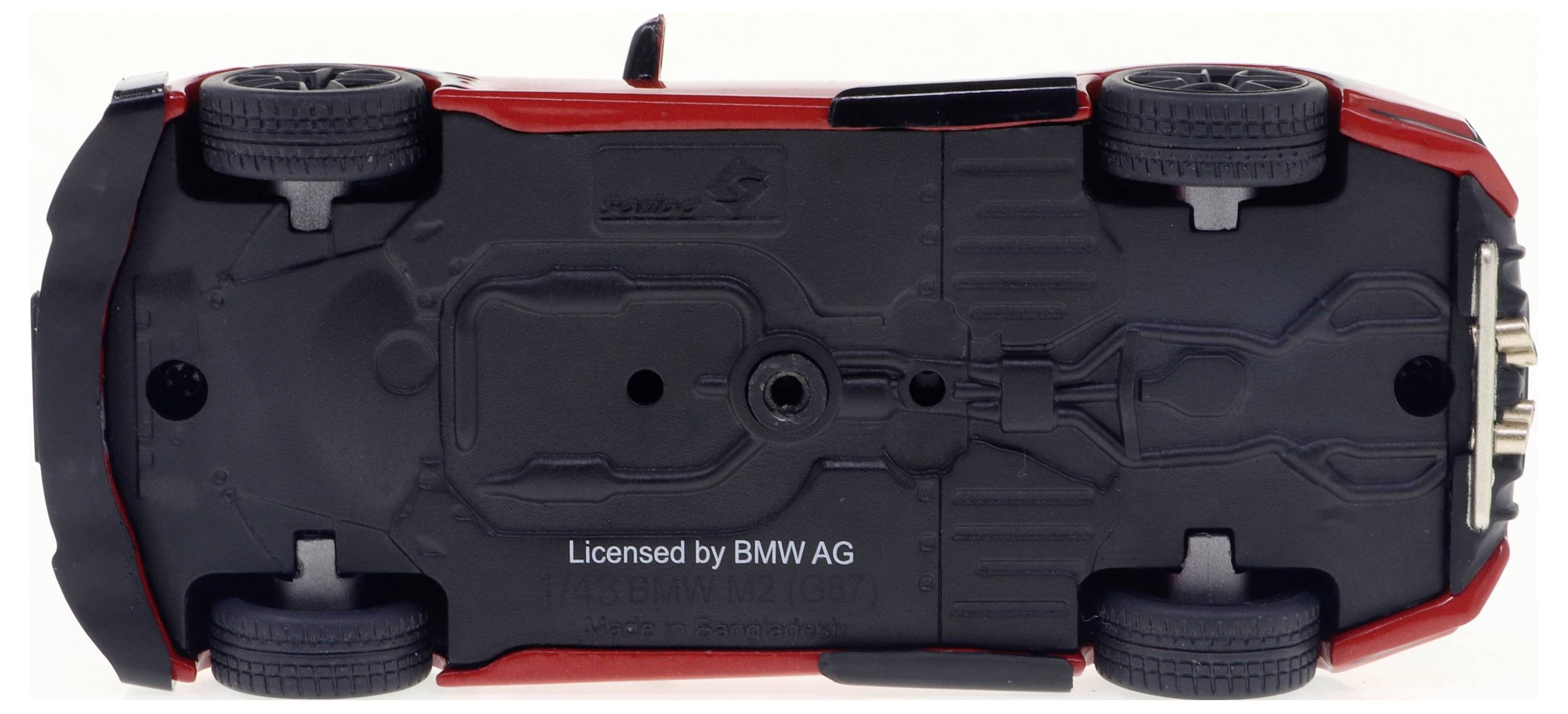 Modèle réduit d'une voiture posé sur son toit. Châssis noir avec quatre roues visibles. Sous licence de 'BMW AG'.