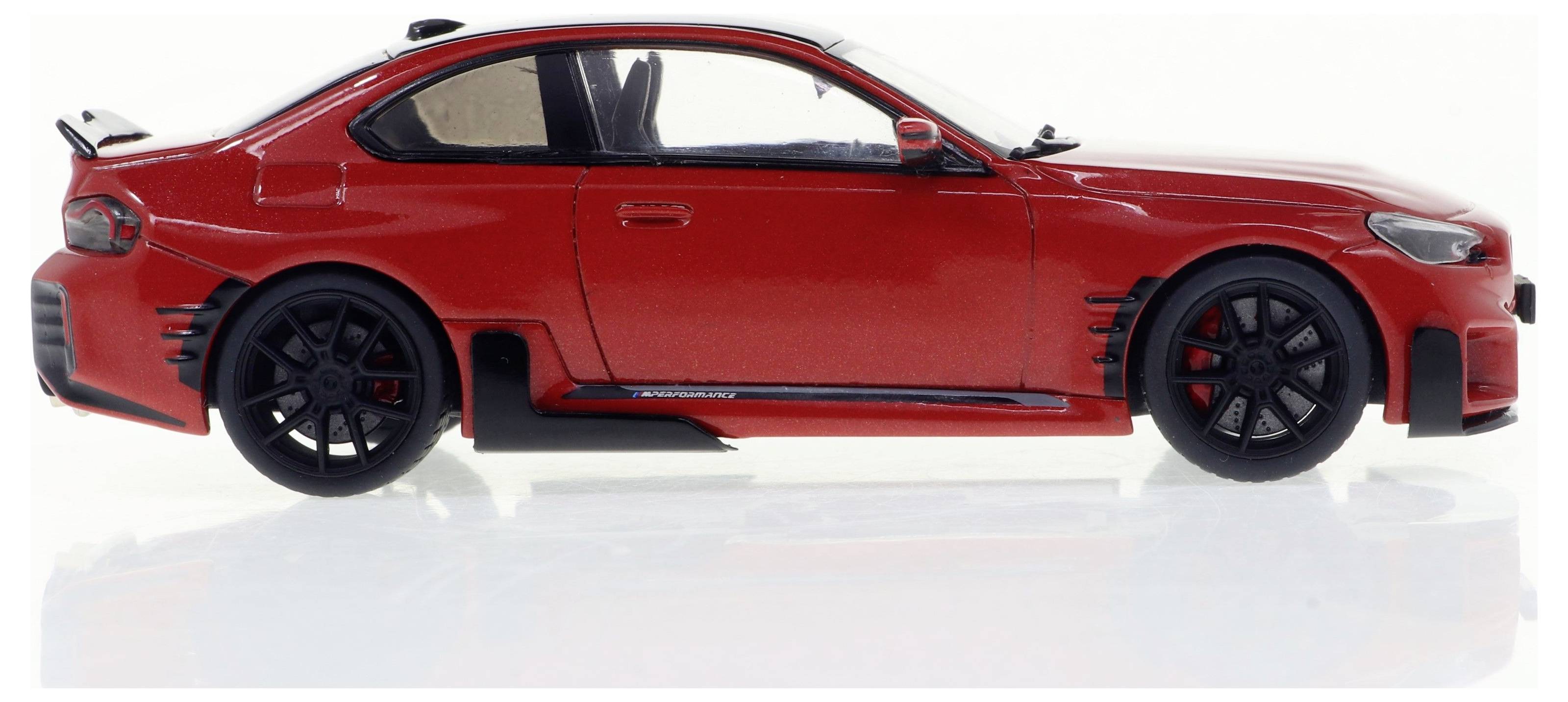 Modèle de voiture de sport rouge en vue latérale, avec des jantes noires et des détails aérodynamiques ; éclairé sur un fond neutre.