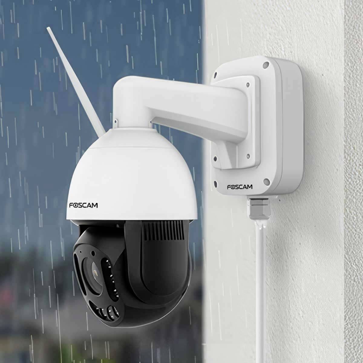 Une caméra de surveillance extérieure Foscam est fixée à un mur et surveille les alentours par temps de pluie.