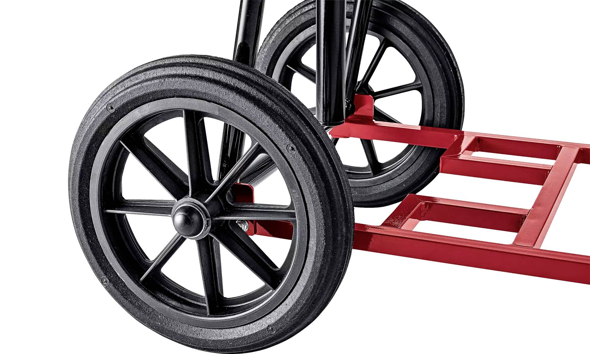 Plan rapproché d'un chariot de transport équipé de grandes roues noires et d'un châssis métallique rouge, conçu pour le transport de charges lourdes.