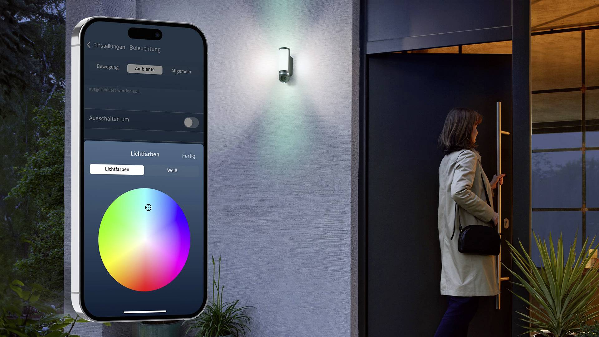 Une femme ouvre sa porte d'entrée, tandis qu'un smartphone affiche la commande d'un éclairage extérieur au moyen d'une palette de couleurs.