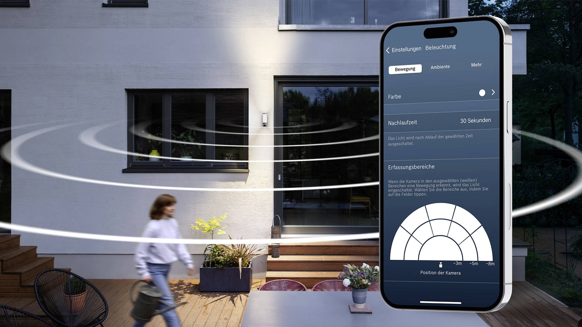 Une femme entre sur une terrasse au crépuscule. Un smartphone affiche une application de contrôle d'éclairage avec des options de mouvement et de couleur.