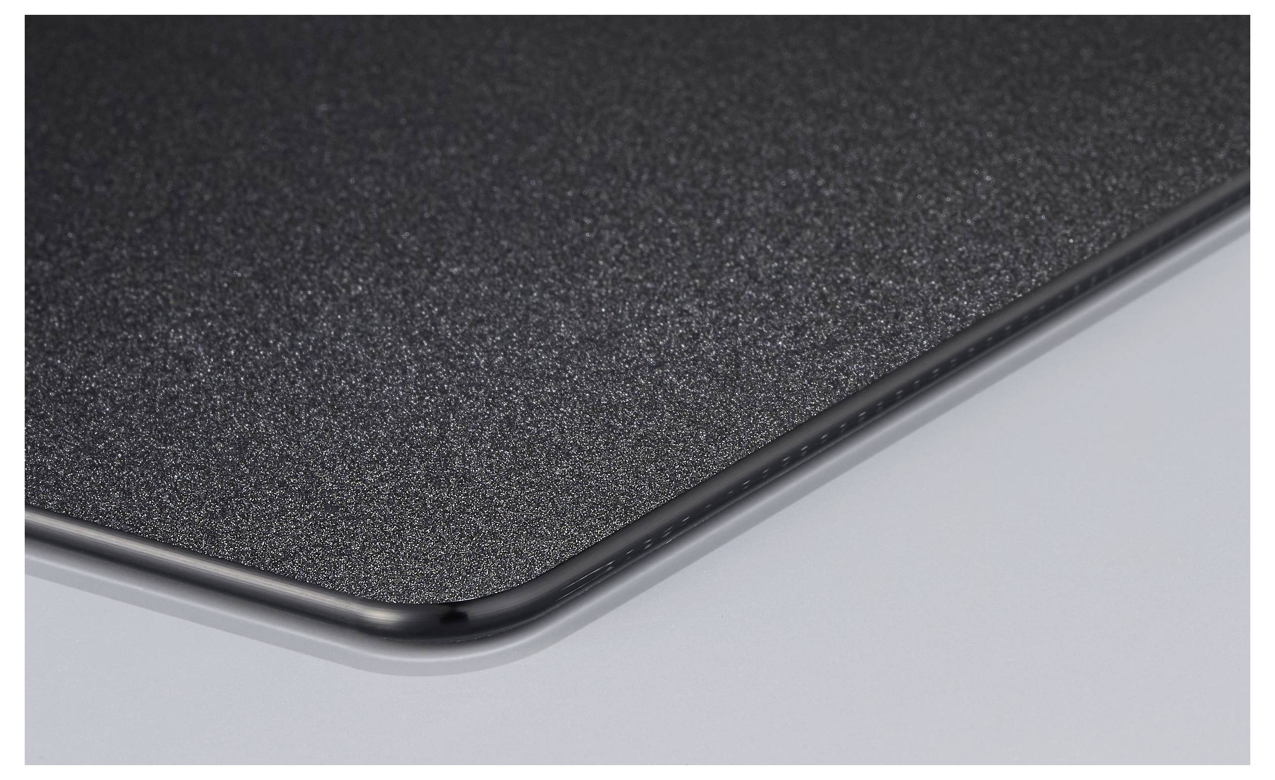 Le coin d'un tapis de souris noir aux bords arrondis sur une surface lisse.