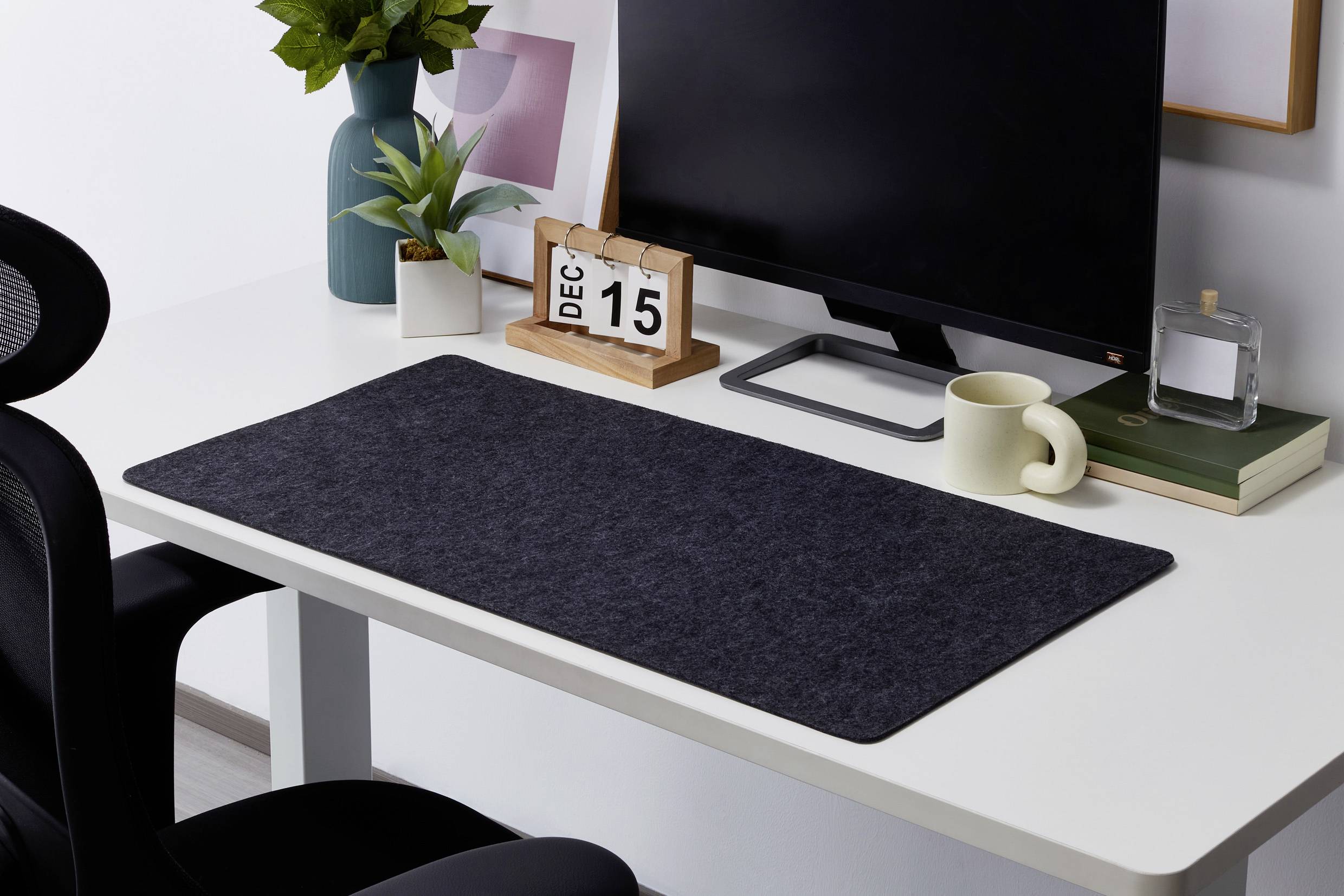 Un bureau bien rangé avec un ordinateur, un calendrier affichant 'DEC 15', des plantes, une tasse et des livres.