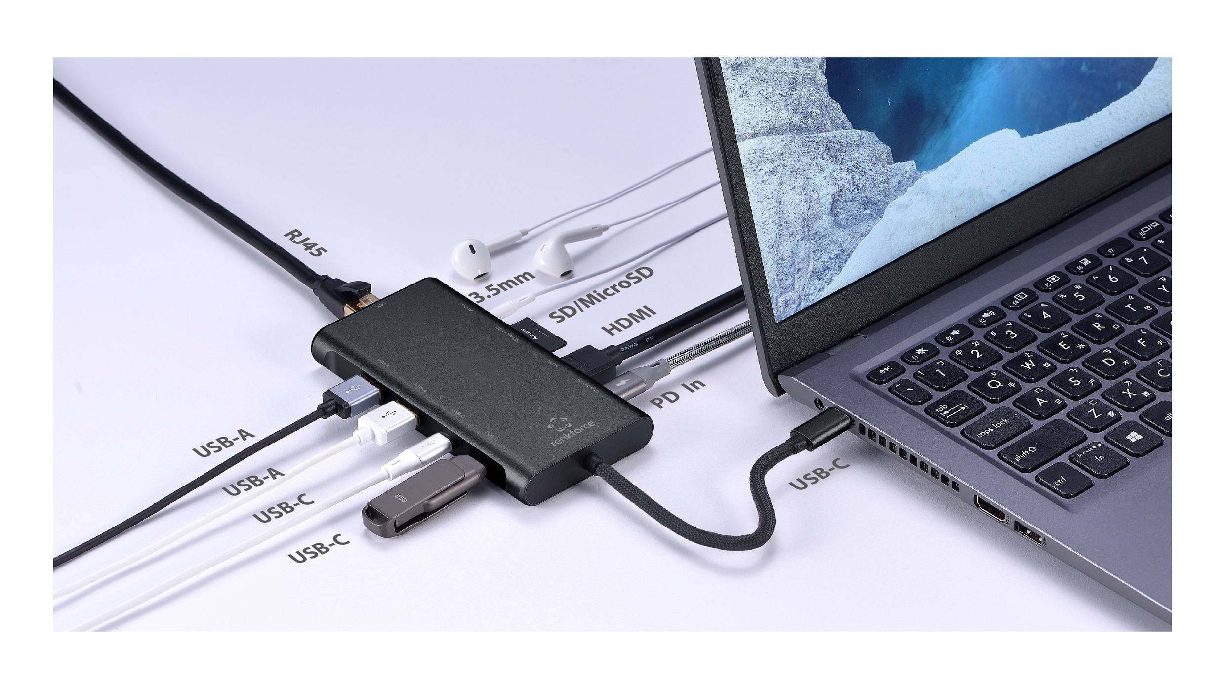 Un ordinateur portable connecté via un hub USB-C avec plusieurs ports : RJ-45, USB-A, USB-C, HDMI, microSD, jack audio 3,5 mm. À proximité, des écouteurs sont branchés.
