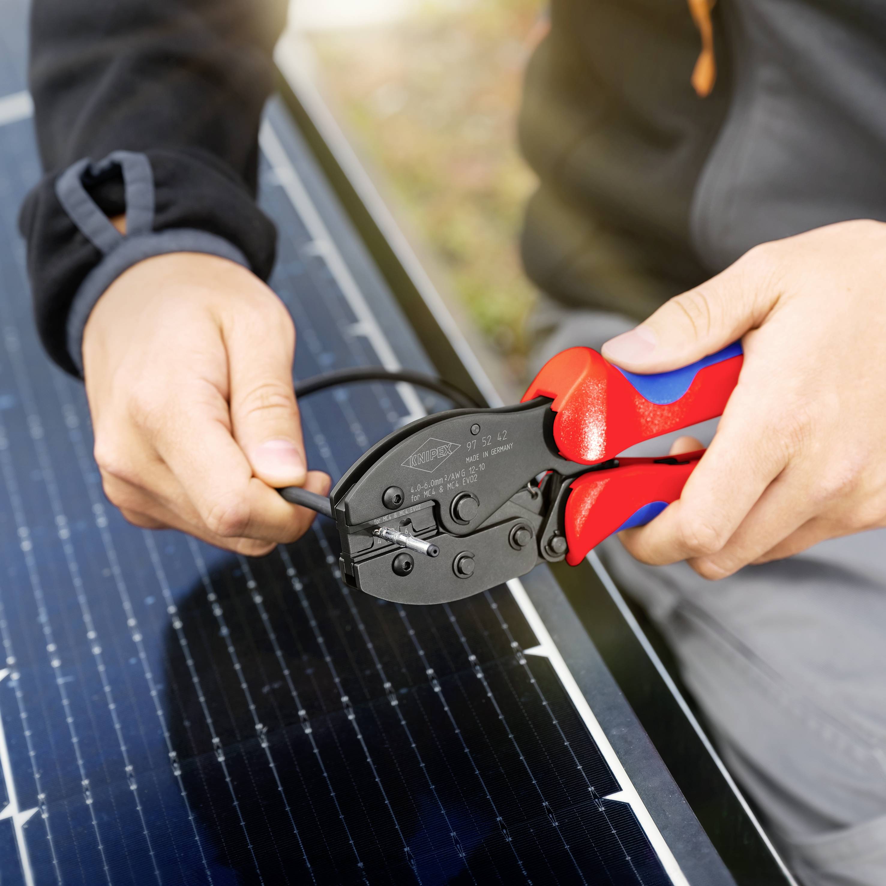 Une personne utilise une pince pour fixer un câble sur un panneau solaire, symbolisant la technologie et les énergies renouvelables.