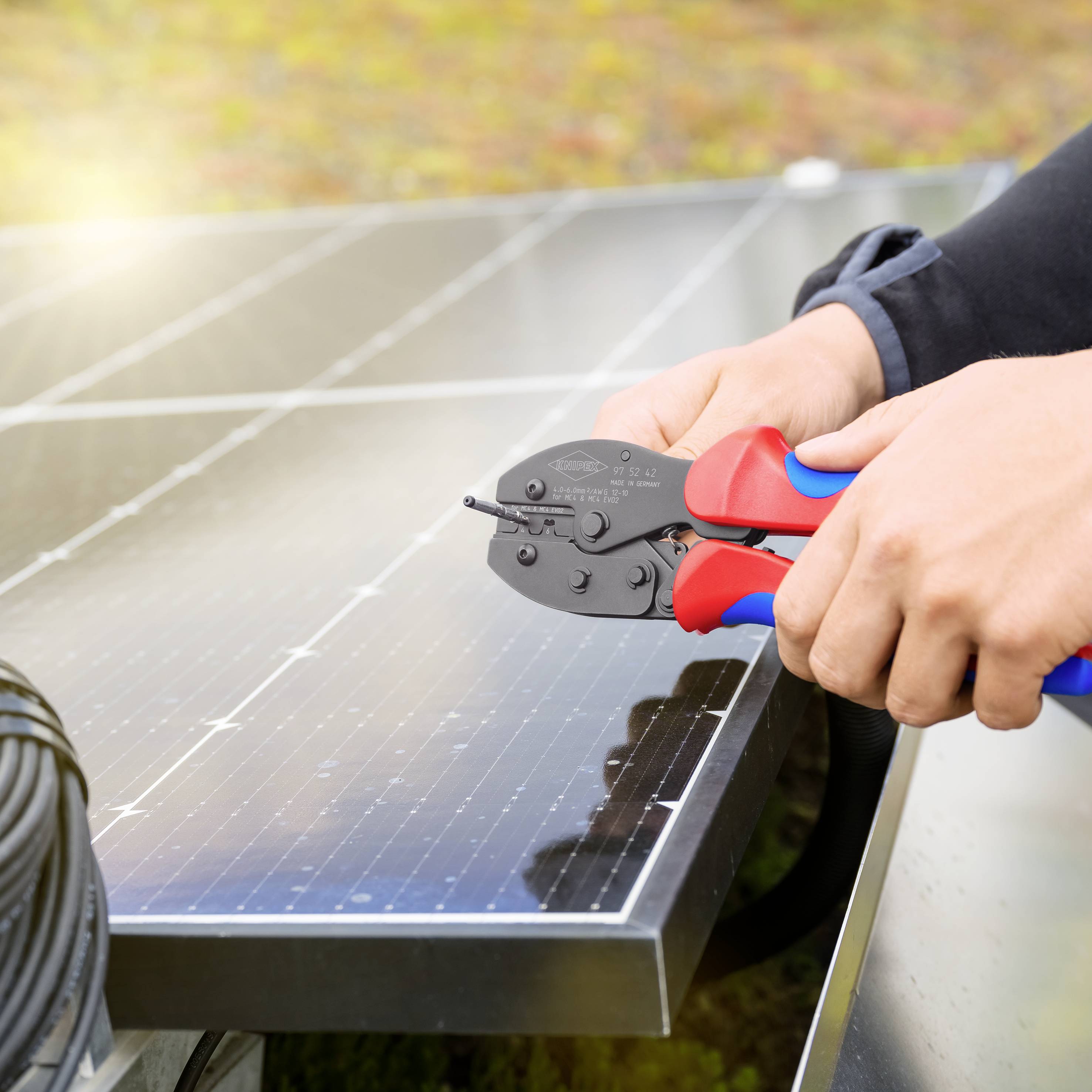 Une personne installe des modules solaires sur un toit, utilisant un outil pour connecter les câbles, tandis que la lumière du soleil est réfléchie.