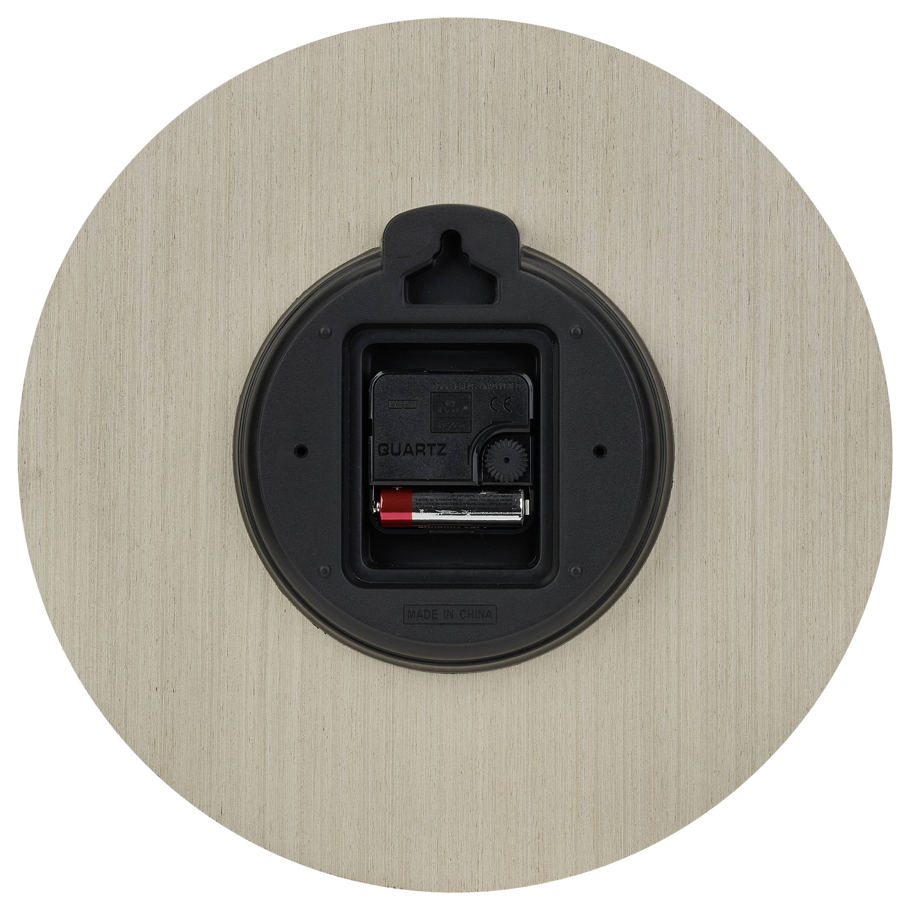 Dos d'une horloge ronde avec compartiment de batterie et mécanisme visibles. Surface à l'apparence de bois.